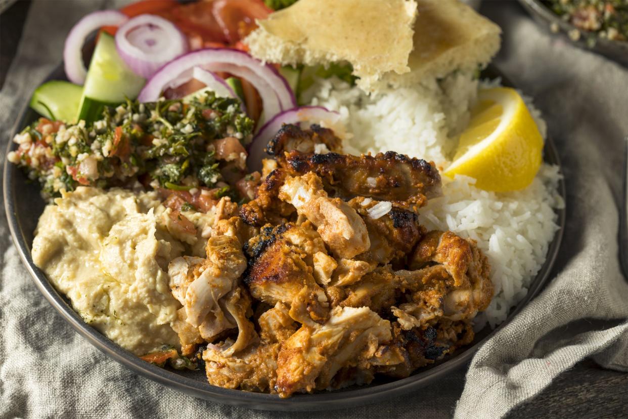 Oven roasted chicken shawarma with rice and sides in a stainless steel thali on a large natural napkin