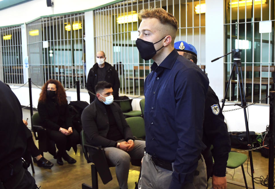 Finnegan Lee Elder, from the United States, walks past to Rosa Maria Esilio, widow of slain Carabinieri military police officer Mario Cerciello Rega, background left, and Paolo Cerciello Rega, brother of Mario, center, prior to a hearing in the trial where he and Gabriel Natale-Hjorth are accused of slaying a plainclothes Carabinieri officer while on vacation in Italy in July 2019, in Rome, Monday, March 1, 2021. (Alberto Pizzoli/Pool Photo via AP)