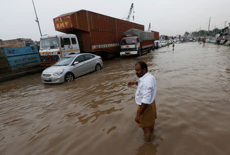 A man directs the vehicles in a waterlogged highway after heavy rains in Gurugram, previously known as Gurgaon, on the outskirts of New Delhi, India, July 29, 2016. REUTERS/Adnan Abidi