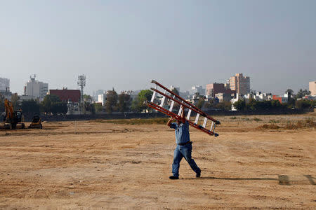 An employee carries a ladder at the site where the new U.S. embassy will be built, during a ceremony to place the first stone of the embassy in Mexico City, Mexico February 13, 2018. REUTERS/Edgard Garrido