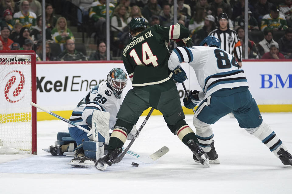 San Jose Sharks goaltender Mackenzie Blackwood (29) and defenseman Jan Rutta (84) defend against Minnesota Wild center Joel Eriksson Ek (14) during the first period of an NHL hockey game Thursday, March 28, 2024, in St. Paul, Minn. (AP Photo/Abbie Parr)