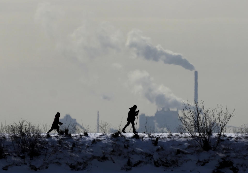 People cross-country ski in the cold weather as an industrial plant is shown in the back ground in Toronto, on Friday, Feb. 4, 2022. (Nathan Denette/The Canadian Press via AP)