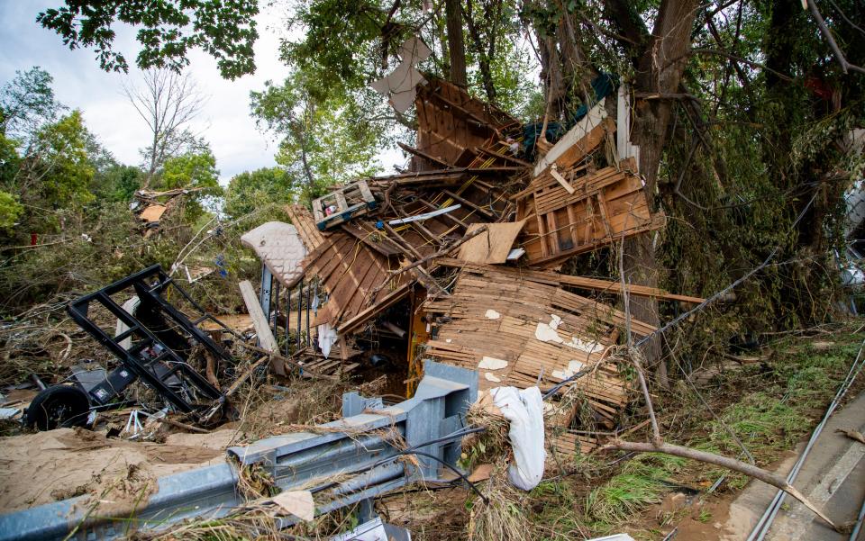 Debris piles up along Swannanoa River Road in downtown Asheville Sunday afternoon.