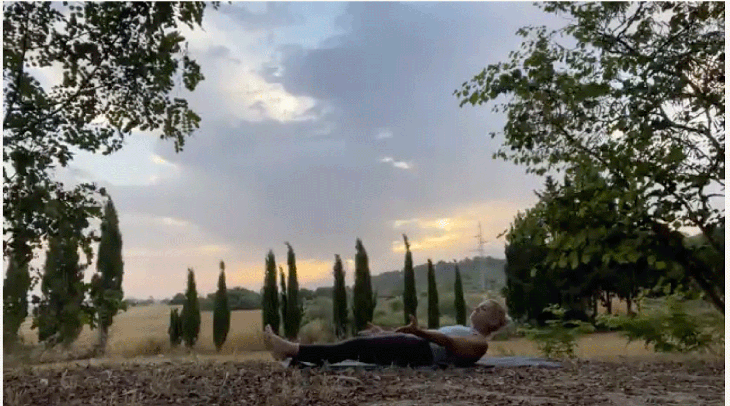 Woman practicing yoga outside on her mat at sunrise