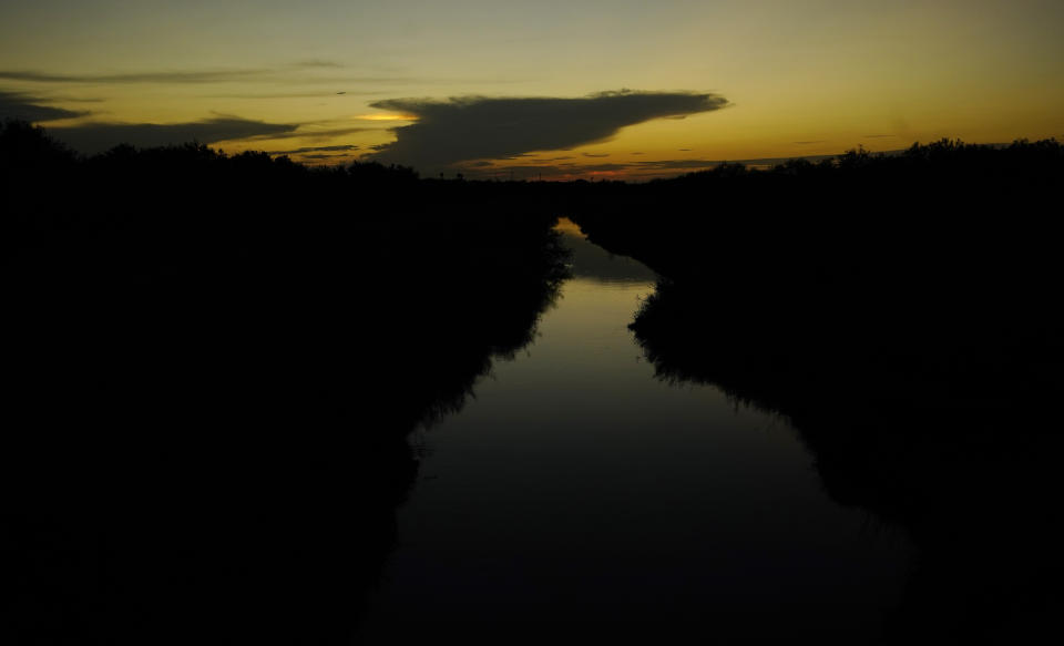 The sun sets over a canal, Tuesday, Sept. 14, 2021, in McAllen, Texas. Canals used to deliver water in many parts of the Rio Grande Valley lose anywhere from 10% to 40% of the water they carry to seepage and evaporation, according to the Texas Water Development Board, making water a growing concern amid climate change and rising demand that scientists predict will lead to water shortages in the region by 2060. (AP Photo/Eric Gay)