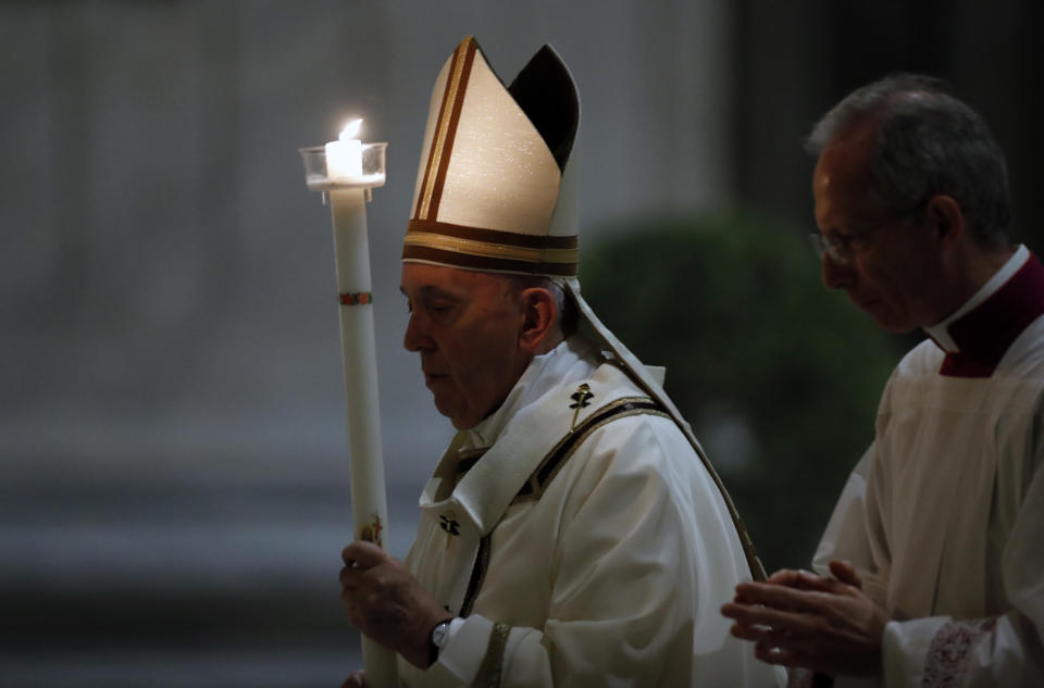 Pope Francis holds a candle as he presides over a solemn Easter vigil ceremony in St. Peter's Basilica empty of the faithful following Italy’s ban on gatherings to contain coronavirus contagion, at the Vatican, Saturday, April 11, 2020. The new coronavirus causes mild or moderate symptoms for most people, but for some, especially older adults and people with existing health problems, it can cause more severe illness or death. (Remo Casilli/Pool Photo via AP)