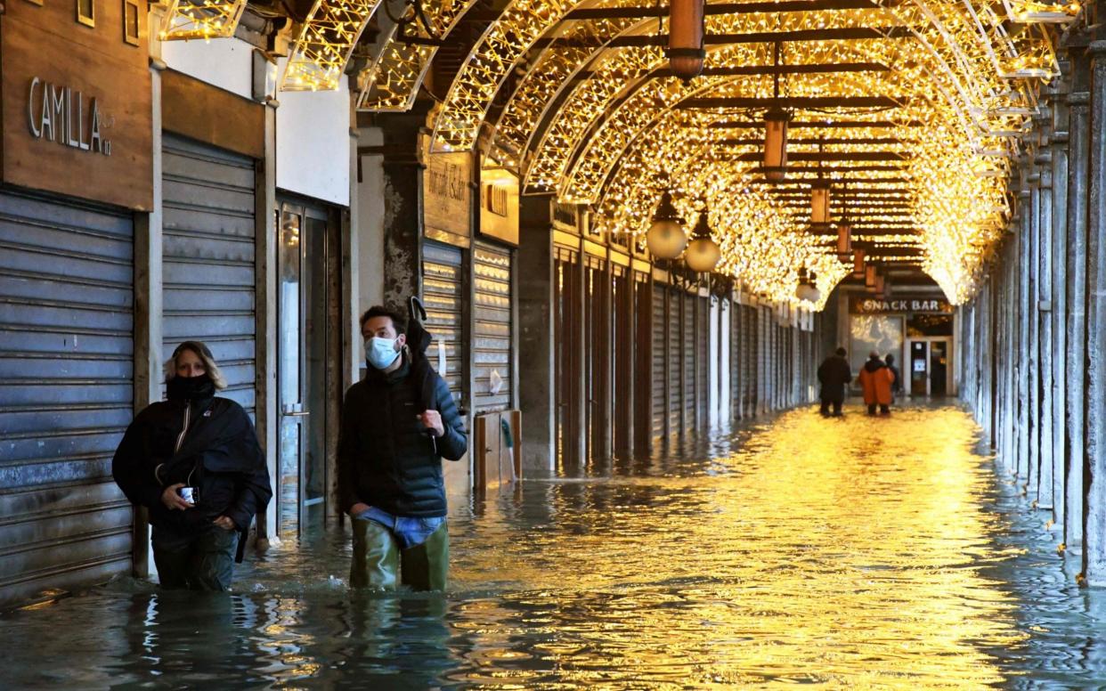 People walk through one of the arcades on a flooded St. Mark's Square  - ANDREA PATTARO /AFP 