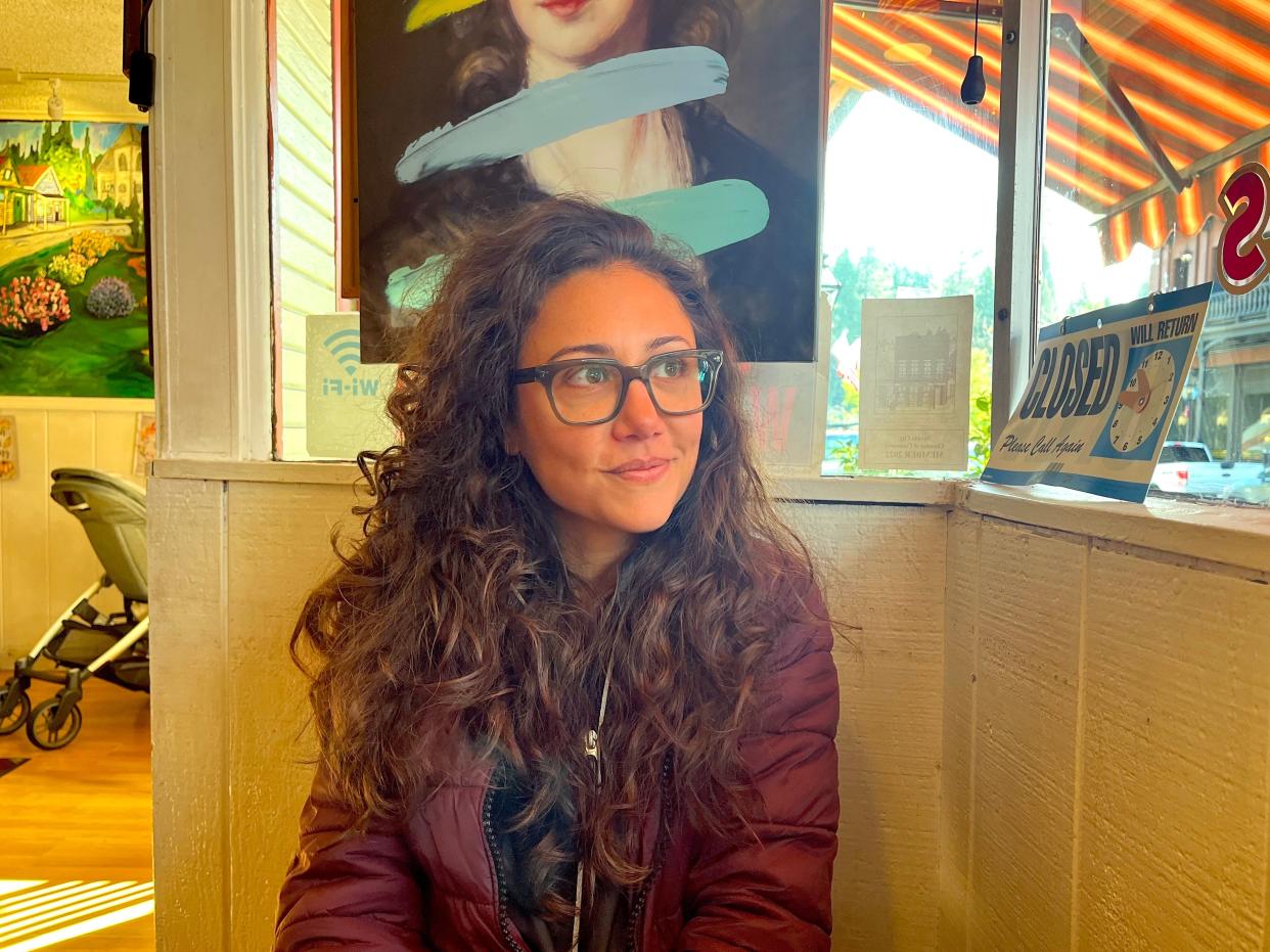 Cristabelle Garcia wearing glasses and a maroon jacket smiling and staring out the window.