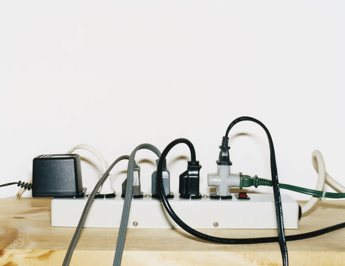 A power strip with multiple electronic devices plugged in, resting on a wooden surface