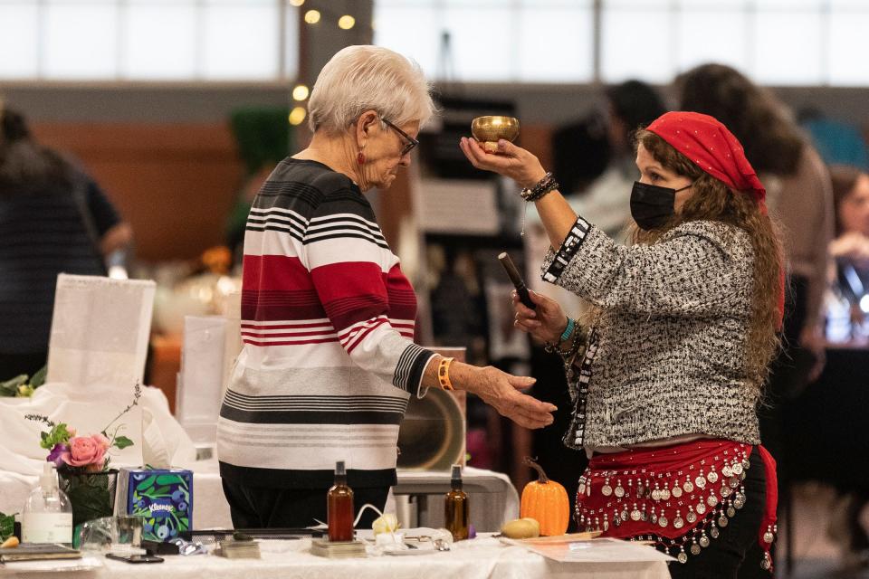 Psychic reader Valerie Robinson of Bloomfield Hills, right, performs a healing process on Joanne McLane of New Baltimore during the Psychic and Holistic Spooktacular at Royal Oak Farmers Market in Royal Oak on Wednesday, Oct. 25, 2023.