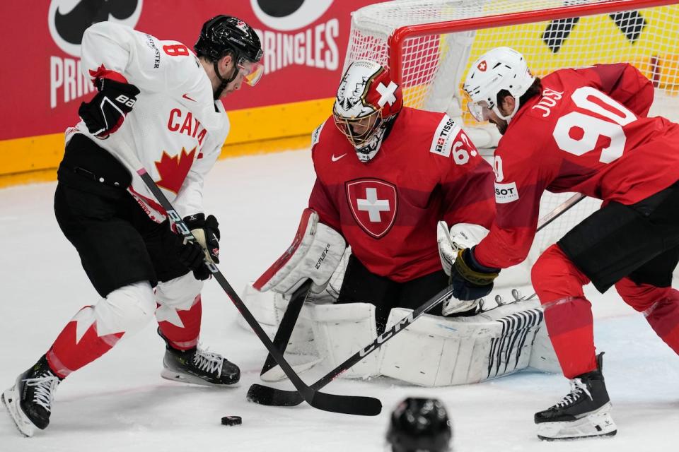 Switzerland's goalkeeper Leonardo Genoni, centre, makes a save in front of Canada's Michael Bunting during the semifinal match on Saturday.  (Darko Vojinovic/The Associated Press - image credit)