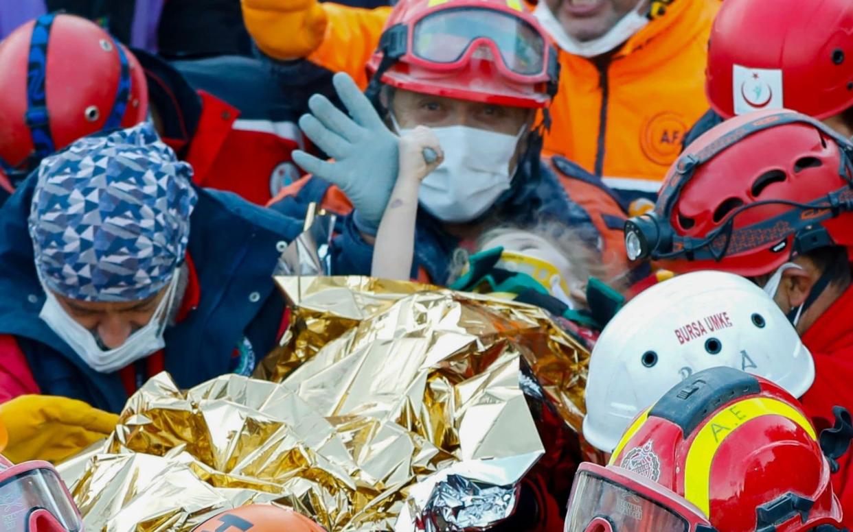 Elif Perincek holds the thumb of a rescue worker as she is carried out of a collapsed building in Izmir, Turkey, following an earthquake  - AFP