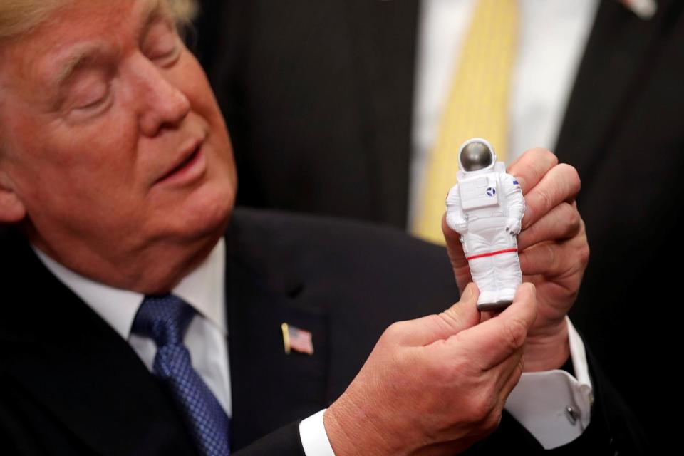 President Donald Trump holds a space astronaut toy as he signs a new space policy directive (REUTERS)