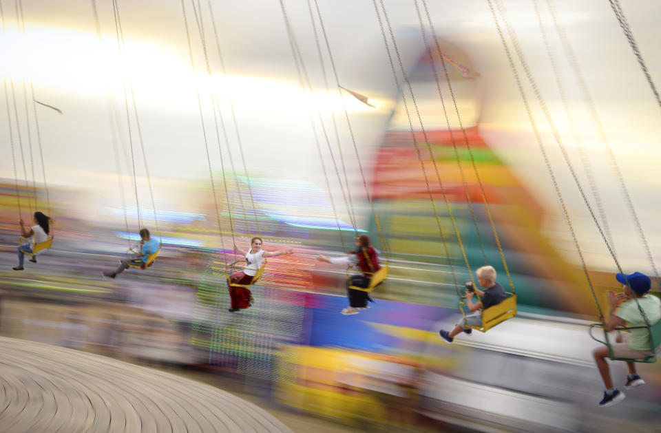 In this picture taken Saturday, Sept. 14, 2019, shot with a slow shutter speed, people enjoy a swing ride at an autumn fair in Titu, southern Romania. Romania's autumn fairs are a loud and colorful reminder that summer has come to an end and, for many families in poorer areas of the country, one of the few affordable public entertainment events of the year. (AP Photo/Andreea Alexandru)