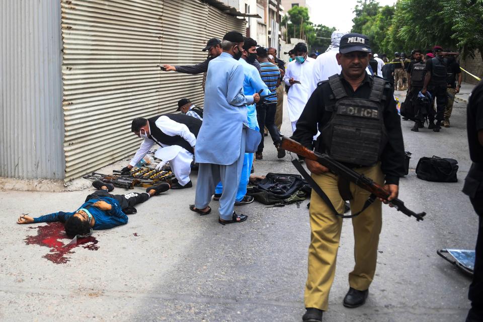 EDITORS NOTE: Graphic content / Policemen gather around the body of an alleged gunman outside the Pakistan Stock Exchange building in Karachi on June 29, 2020. - Gunmen attacked the Pakistan Stock Exchange in Karachi on June 29, with four of the assailants killed, police said. (Photo by Asif HASSAN / AFP) (Photo by ASIF HASSAN/AFP via Getty Images)