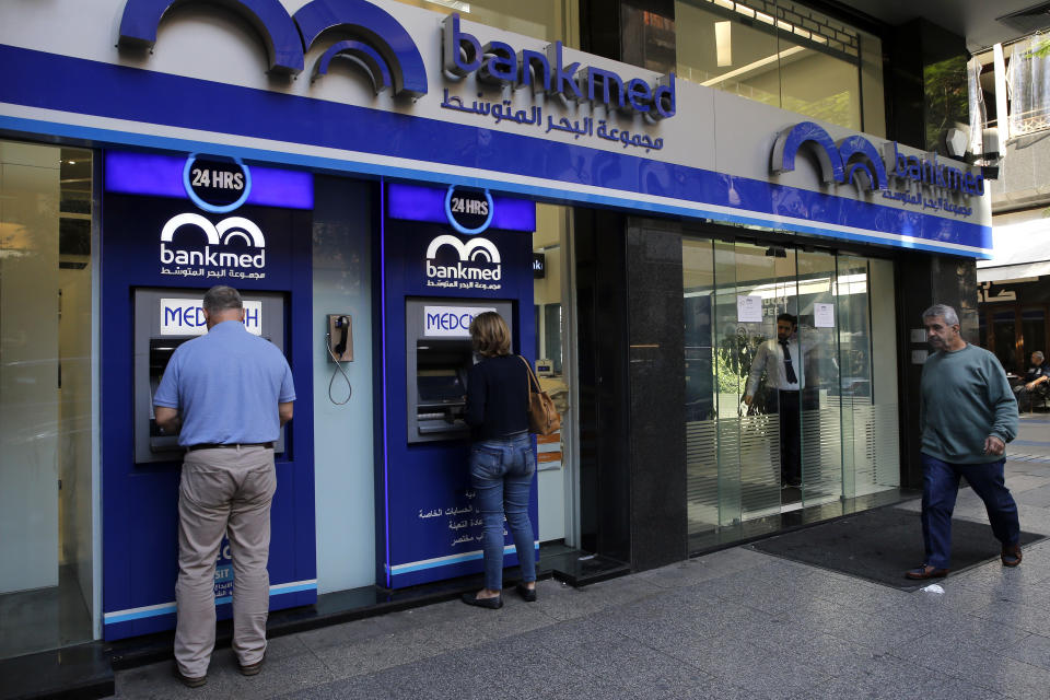 People use an ATM outside a bank, in Beirut, Lebanon, Wednesday, Nov. 20, 2019. Lebanon’s worsening financial crisis has thrown businesses and households into disarray. Banks are severely limiting withdrawals of hard currency, and Lebanese say they don’t know how they’ll pay everything from tuitions to insurance and loans all made in dollars. Politicians are paralyzed, struggling to form a new government in the face of tens of thousands of protesters in the streets for the past month demanding the entire leadership go. (AP Photo/Bilal Hussein)