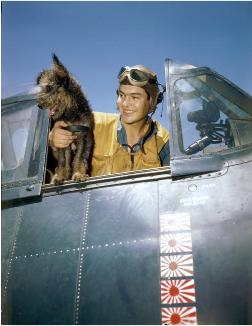 A dog and a US service member pose for a photo in a warplane.