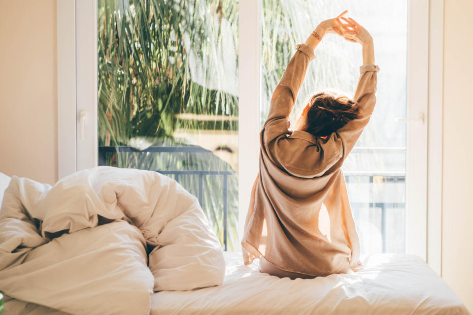 Woman stretching after getting up out of bed. (Getty Images)