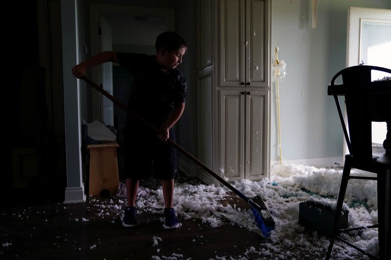 Lane Kingham cleans up ceiling insulation from his kitchen floor after Hurricane Laura passed through the area in Cameron Parish