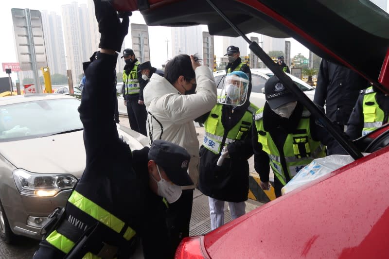 Police officers wearing masks check the boot of a car for smuggled wild animals following the outbreak of a new coronavirus, at an expressway toll station on the eve of the Chinese Lunar New Year celebrations, in Xianning