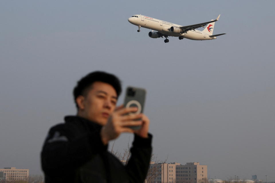 A man takes a selfie as a plane of China Eastern Airlines lands at the Beijing Capital International Airport in Beijing, China March 23, 2022. REUTERS/Tingshu Wang     TPX IMAGES OF THE DAY