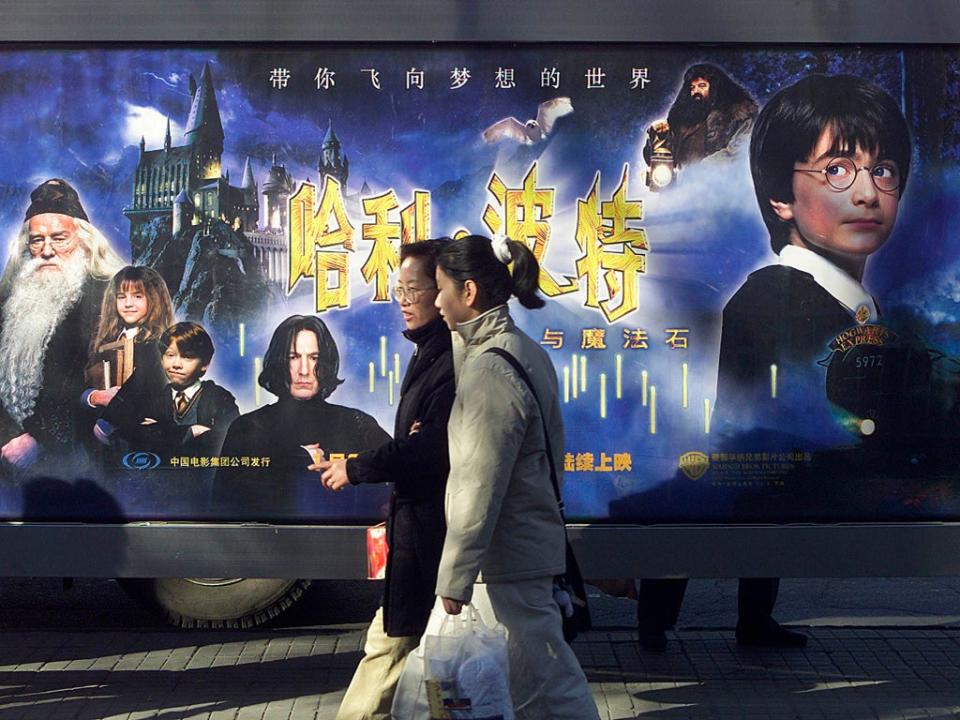 Women walk past a ‘Harry Potter and the Philosopher’s Stone’ billboard in Shanghai in early 2002 (Frederic Brown/AFP/Getty)