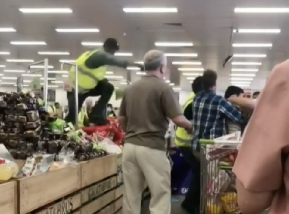 A worker leaps over produce to try and break up the altercation at Spudshed, Perth. Source: Nine News