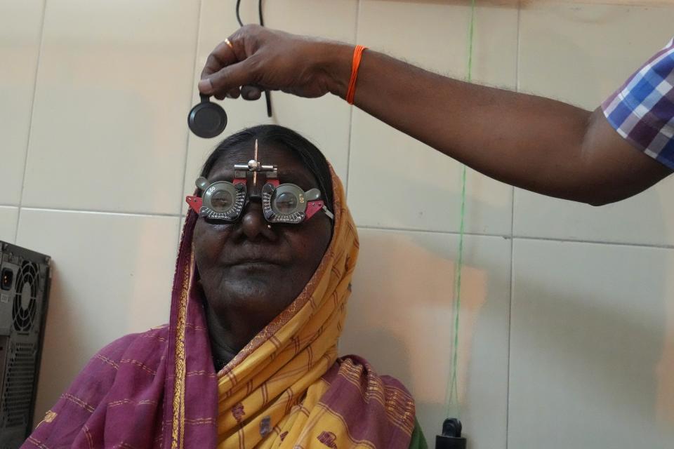 An optometrist checks the eyesight of an elderly woman at a health care center which runs on rooftop solar power, near Raichur, India, Thursday, April 20, 2023. In semi-urban and rural regions of India and other developing countries with unreliable power grids, decentralized renewable energy — especially solar — is making all the difference in delivering modern health care.(AP Photo/Aijaz Rahi)