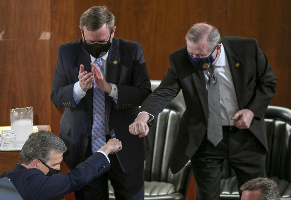 FILE - Sen. Phil Berger, right, fist bumps North Carolina Gov. Roy Cooper after Cooper delivered his State of the State address before a joint session of the North Carolina House and Senate, Monday, April 26, 2021, in Raleigh, N.C. As the year draws to a close in politically divided North Carolina, hostilities have eased somewhat between the Democratic governor and majority-Republican lawmakers, both of whom recently agreed on a comprehensive budget more than three years after the last one was approved. (Robert Willett/The News & Observer via AP, File)