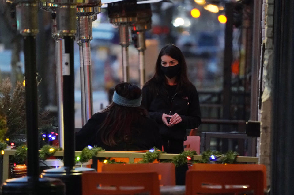 FILE - In this Monday, Dec. 28, 2020, file photo, a server wears a face mask while tending to a patron sitting in the outdoor patio of a sushi restaurant, in downtown Denver. Restaurants devastated by the coronavirus outbreak are getting a lifeline from the pandemic relief package awaiting final approval in the House. (AP Photo/David Zalubowski, File)