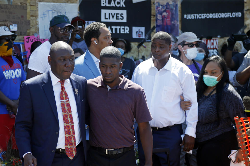 Family attorney Ben Crump, left, escorts Quincy Mason, second from left, a son of George Floyd, Wednesday, June 3, 2020, in Minneapolis, as they and some Floyd family members visited a memorial where Floyd was arrested on May 25 and died while in police custody. Video shared online by a bystander showed a white officer kneeling on his neck during his arrest as he pleaded that he couldn't breathe. (AP Photo/Jim Mone)