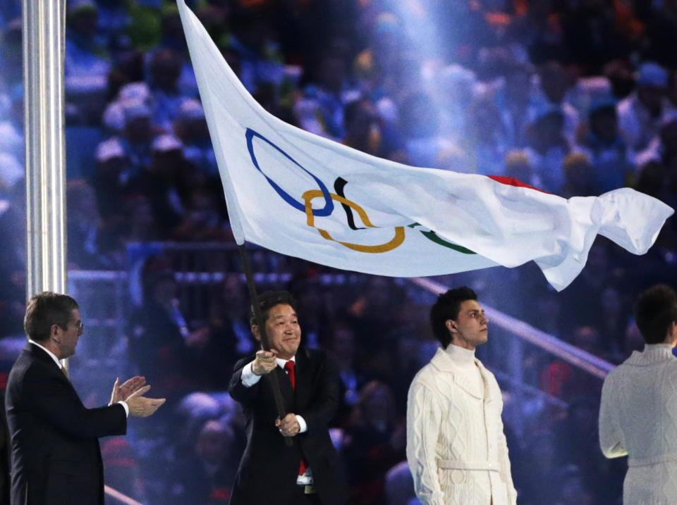 The mayor of Pyeongchang Lee Seok-rai, centre, waves the Olympic flag as International Olympic Committee President Thomas Bach, left, applauds during the closing ceremony of the 2014 Winter Olympics, Sunday, Feb. 23, 2014, in Sochi, Russia. (AP Photo/Matt Dunham)