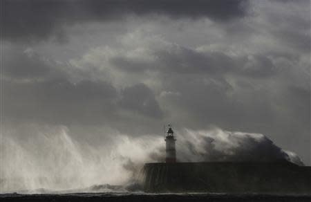 Waves crash against a lighthouse during storms that battered Britain and where a 14-year-old boy was swept away to sea, at Newhaven in South East England October 28, 2013. REUTERS/Luke MacGregor