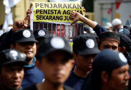 A protester holds a banner outside a court during the first day of the blasphemy trial of Jakarta's Governor Basuki Tjahaja Purnama, also known as Ahok, in Jakarta, Indonesia December 13, 2016. REUTERS/Darren Whiteside