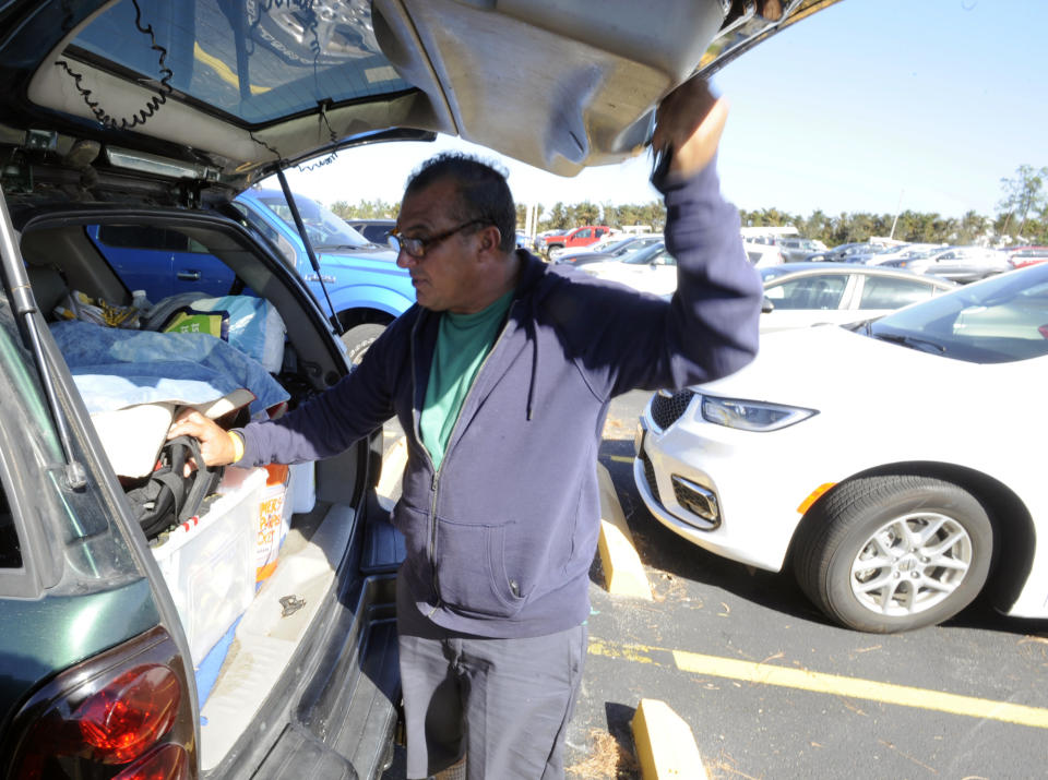 Left homeless by Hurricane Ian, Danilo Mendoza checks for tools in his vehicle outside a relief shelter in Estero, Fla., on Saturday, Oct. 8, 2022. Mendoza, a construction worker from the Miami area whose trailer and tools were blown away by Ian, has seen the places where people are going on with life, where the recovery already is underway, but he’s doing his best to stay positive. (AP Photo/Jay Reeves)