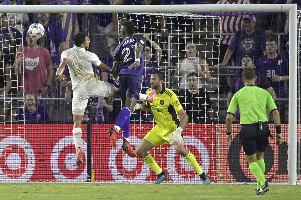 Orlando City midfielder Andres Perea (21) attempts a header on goal between Atlanta United defender Ronald Hernandez (2) and goalkeeper Alec Kann during the first half of an MLS soccer match Friday, July 30, 2021, in Orlando, Fla. (Phelan M. Ebenhack/Orlando Sentinel via AP)