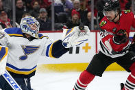 St. Louis Blues goaltender Jordan Binnington, left, reaches for the puck in front of Chicago Blackhawks center Ryan Carpenter during the first period of an NHL hockey game in Chicago, Friday, Nov. 26, 2021. (AP Photo/Nam Y. Huh)