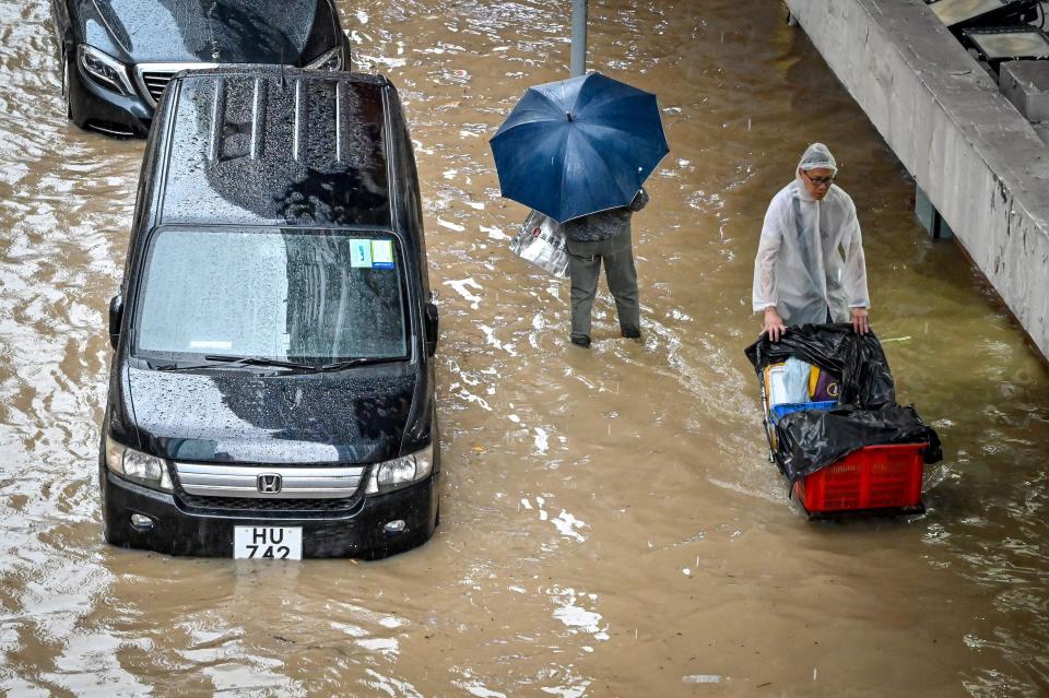 People walk on a flooded road in Hong Kong on September 8, 2023.
