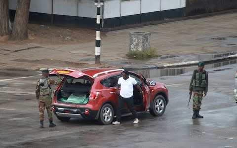 Armed soldiers search a vehicle on the road leading to President Robert Mugabe's office in Harare - Credit: AP