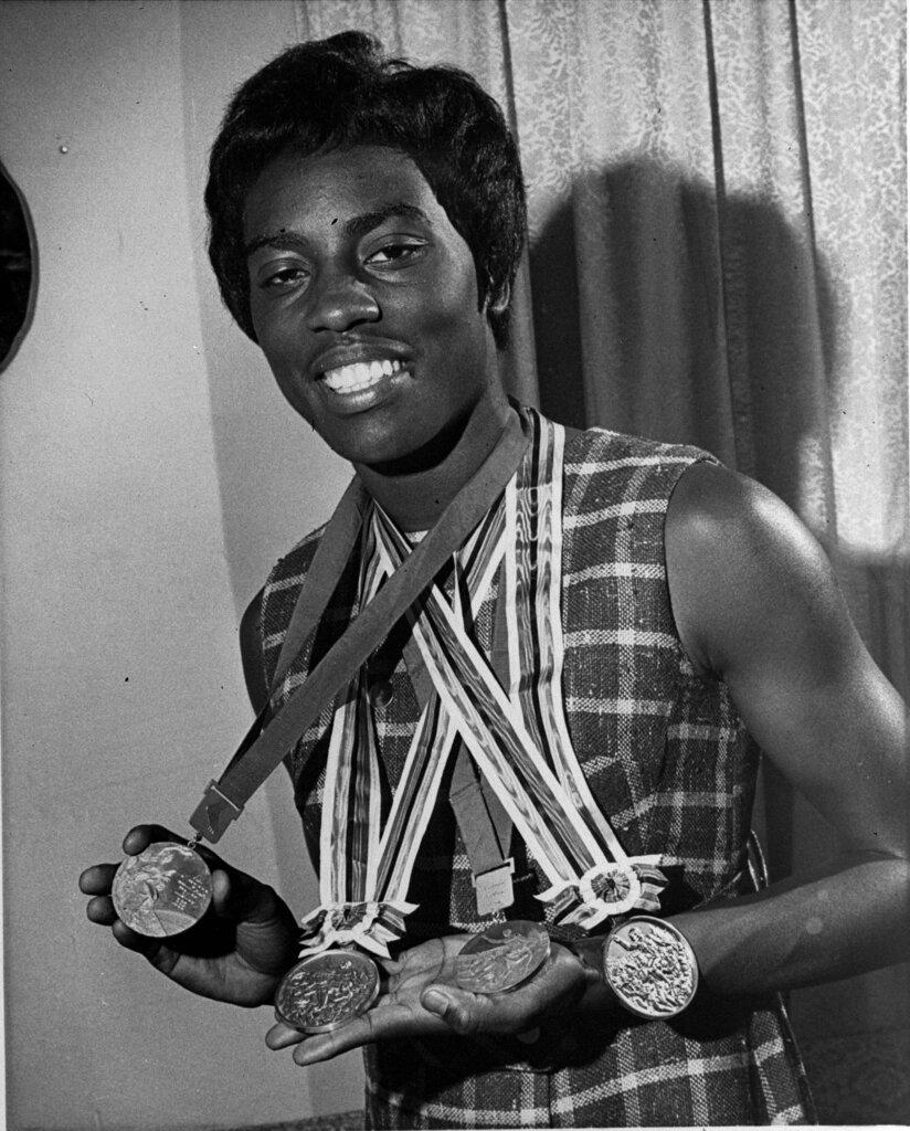 Wyomia Tyus, of Griffin, Ga., displays the three Olympic gold medals and one silver medal she plans to pack away with her track shoes in favor of  