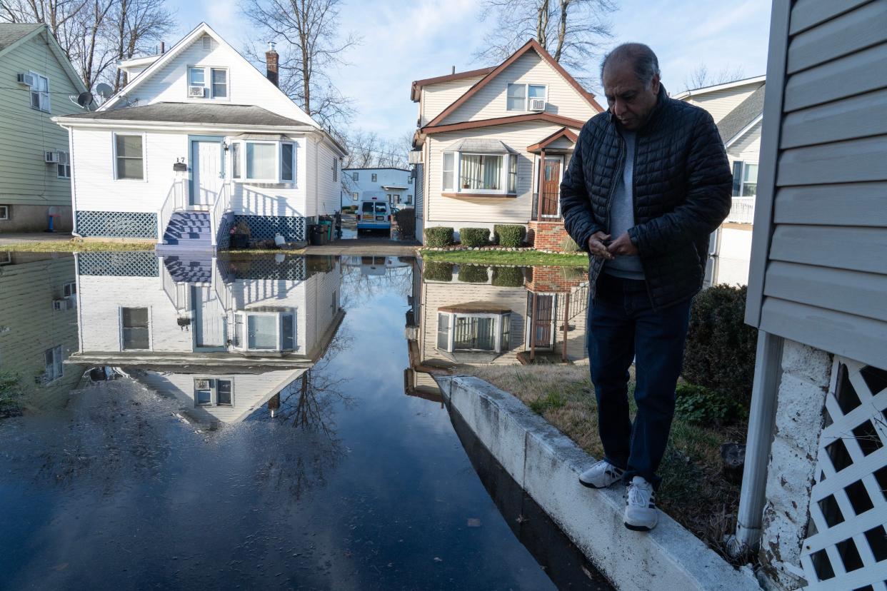 A man walks along the front lawns of home to check on his home for water damage on Zeliff Ave in Little Falls, NJ on Friday Jan. 12, 2024.