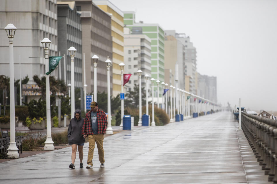 Beach-goers brave the weather and walk along the boardwalk at the Virginia Beach Oceanfront on Friday, Sept. 22, 2023, as Tropical Storm Ophelia approaches. in Virginia Beach, Va. (Kendall Warner/The Virginian-Pilot via AP)