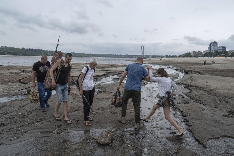 People walk on a central beach as water in Dnipro river dropped more than 4 meters after the explosion of the Kakhovka dam in Zaporizhzhia, Ukraine, Sunday, July 9, 2023. (AP Photo/Evgeniy Maloletka)