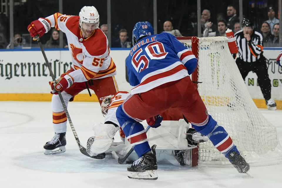 New York Rangers left wing Will Cuylle (50) scores a goal around Calgary Flames goaltender Jacob Markstrom and defenseman Noah Hanifin during the second period an NHL hockey game against the Calgary Flames on Monday, Feb. 12, 2024, in New York. (AP Photo/Bryan Woolston)