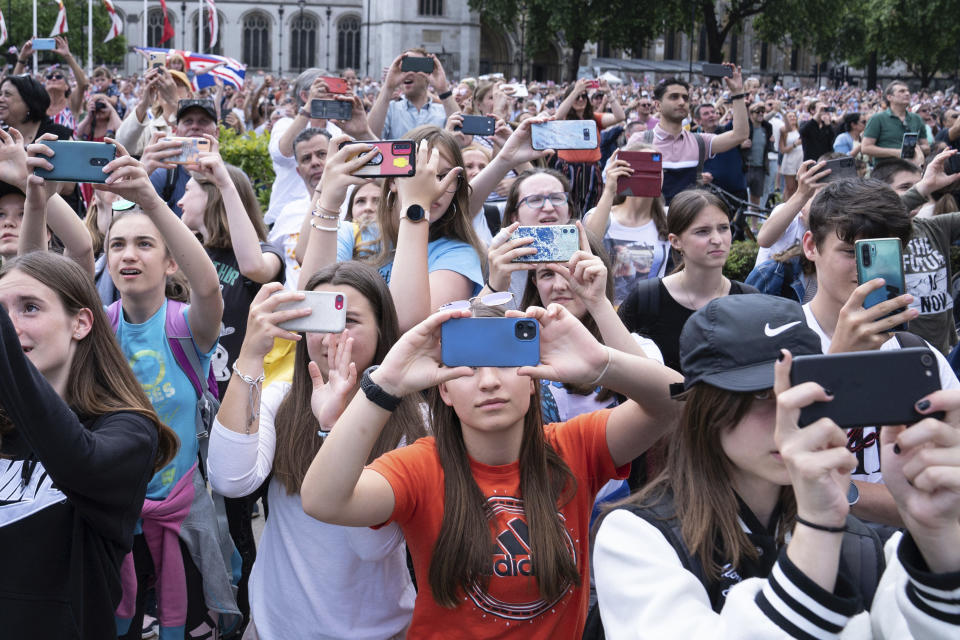 Crowds in Parliament Square take photographs of the Jubilee flypast as it passes over London, Thursday June 2, 2022, on the first of four days of celebrations to mark Queen Elizabeth II's Platinum Jubilee. (Stefan Rousseau/PA via AP)