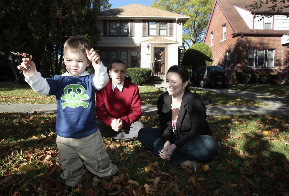 One and a half year old Sean Kvoriak plays with leaves with his parents Joe and Keara in front of their home in the North Rosedale Park neighborhood of Detroit, Michigan on October 16, 2012. Kvoriaks bought their homes in August 2010, a 1,700 square-foot, three-bedroom home for $70,000. REUTERS/Rebecca Cook