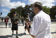 British expatriate Steven Oldrid, right, films a group crossing over the site of the original WWII Pegasus Bridge during D-Day ceremonies in Benouville, Normandy, France on Saturday, June 6, 2020. Due to coronavirus measures many relatives and veterans will not make this years 76th anniversary of D-Day. Oldrid will be bringing it to them virtually as he places wreaths and crosses for families and posts the moments on his facebook page. (AP Photo/Virginia Mayo)