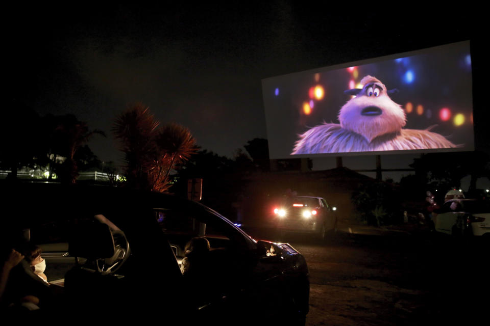 Una familia con mascarillas mira una película en un autocine en Brasilia, 13 de mayo de 2020. (AP Foto/Eraldo Peres)