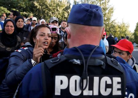 Migrants address a Hungarian police officer at collection point in the village of Roszke, Hungary, September 7, 2015. REUTERS/Marko Djurica