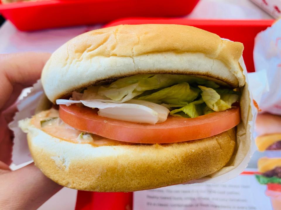 hand holding an In-n-out veggie burger in white parchment paper